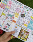 A hand holding a colorful and detailed planners or organizers with various sections for scheduling, reminders, and personal notes.