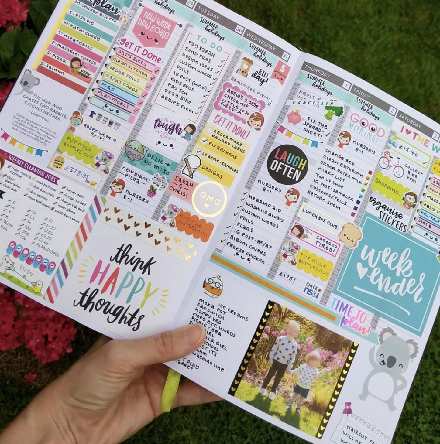 A hand holding a colorful and detailed planners or organizers with various sections for scheduling, reminders, and personal notes.